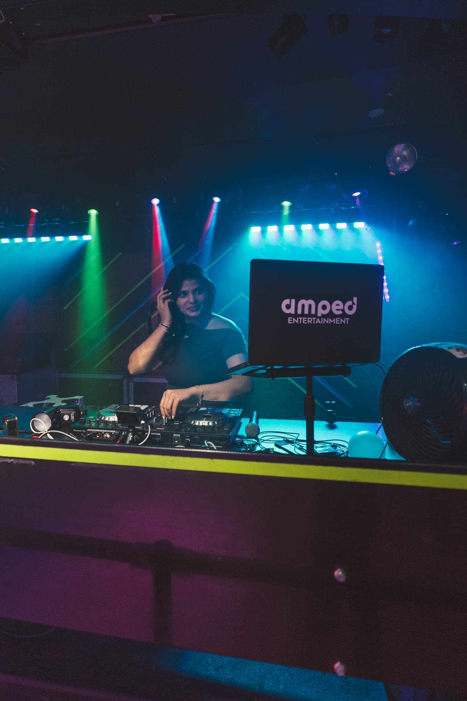 Amped DJ performing behind a branded booth